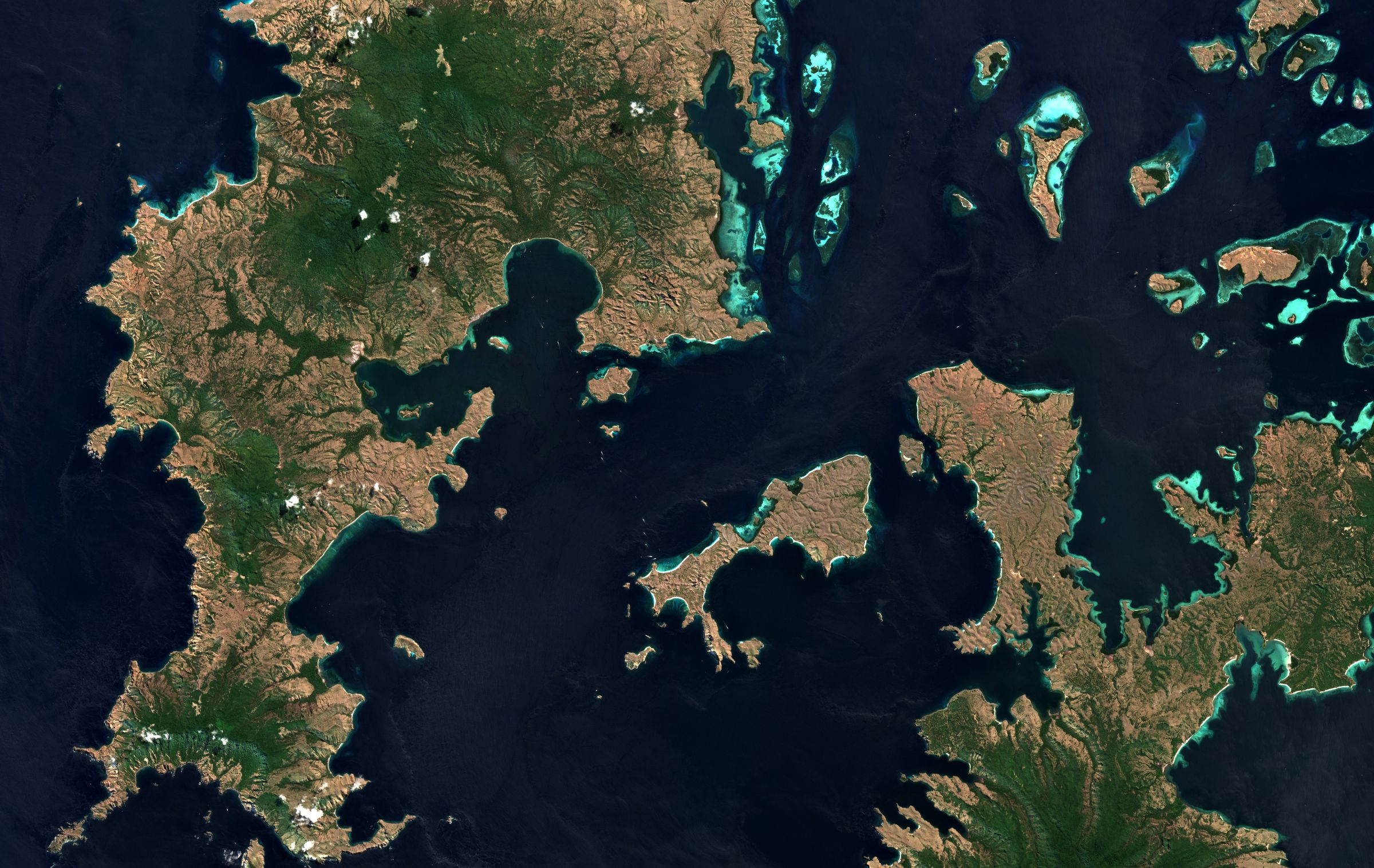 Sentinel-2 true-colour image of Komodo National Park: brown and green islands, turquoise reefs and deep blue sea.